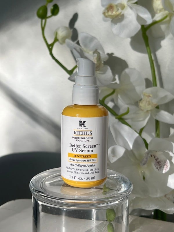 Kiehl's Better Screen UV Serum on a glass riser with white orchids