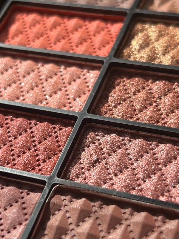 Close up of a pressed eyeshadow palette in warm pink tones
