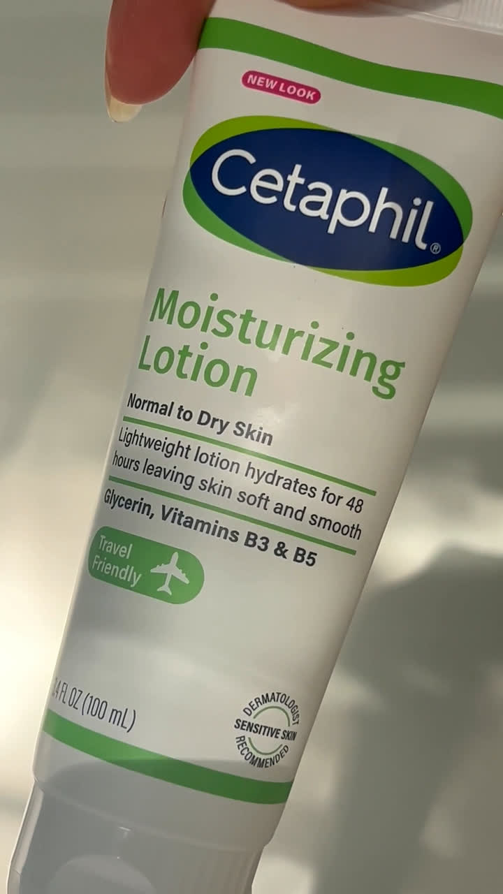 Hand holding a Cetaphil Moisturizing Lotion tube, label facing the camera