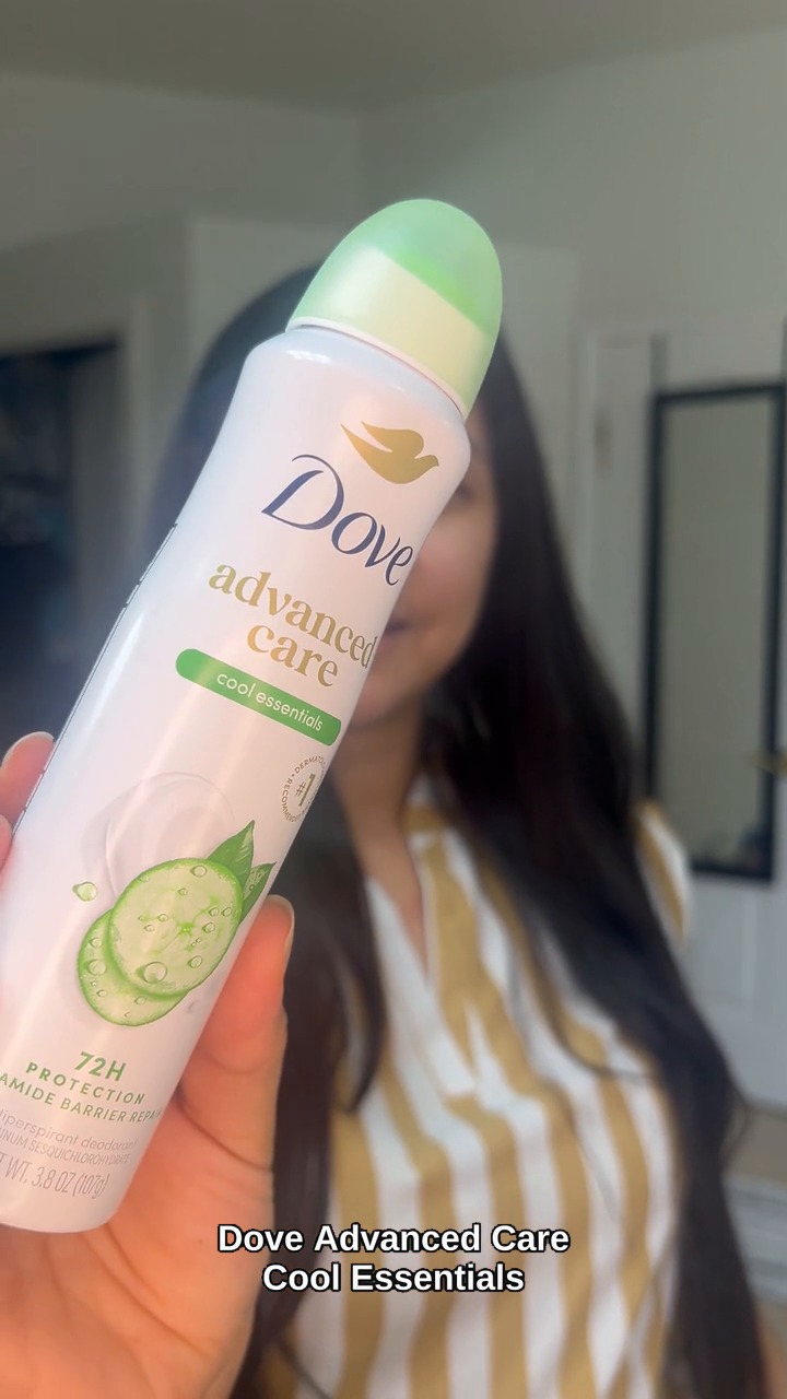 Hand holding a Dove Advanced Care Cool Essentials deodorant spray, label facing the camera