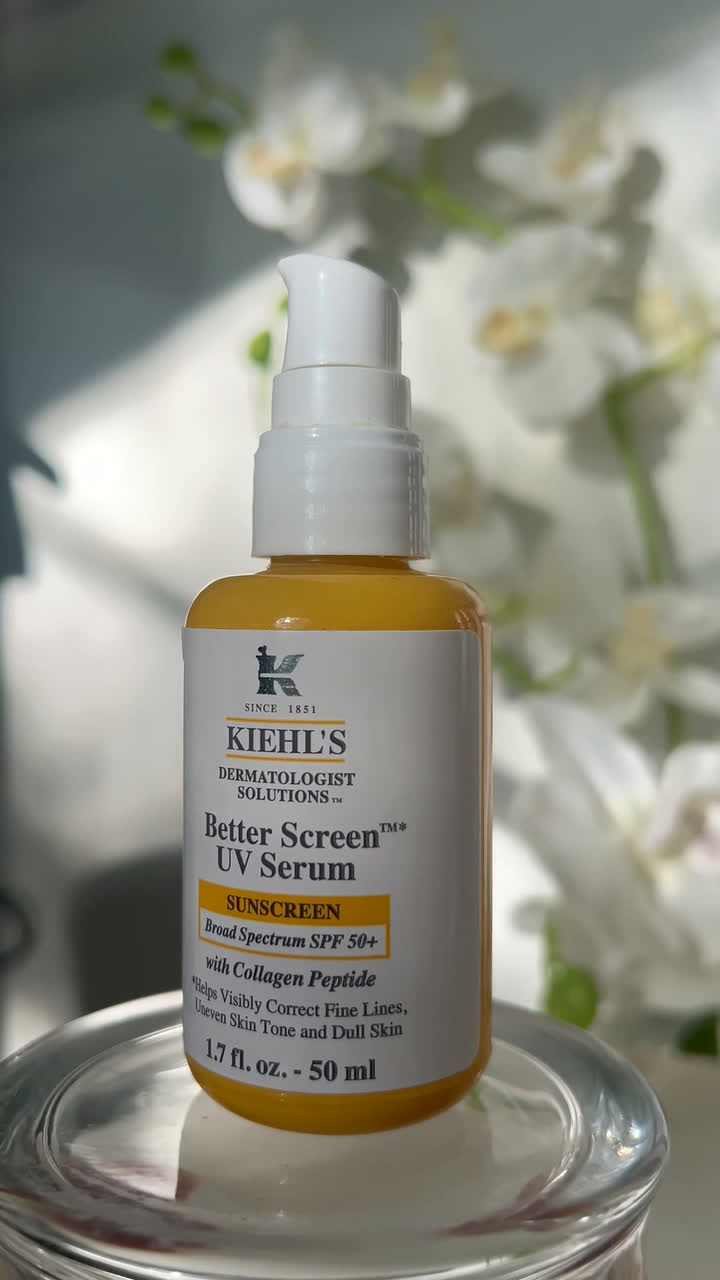 Kiehl's Better Screen UV Serum bottle on a glass riser with white orchids behind